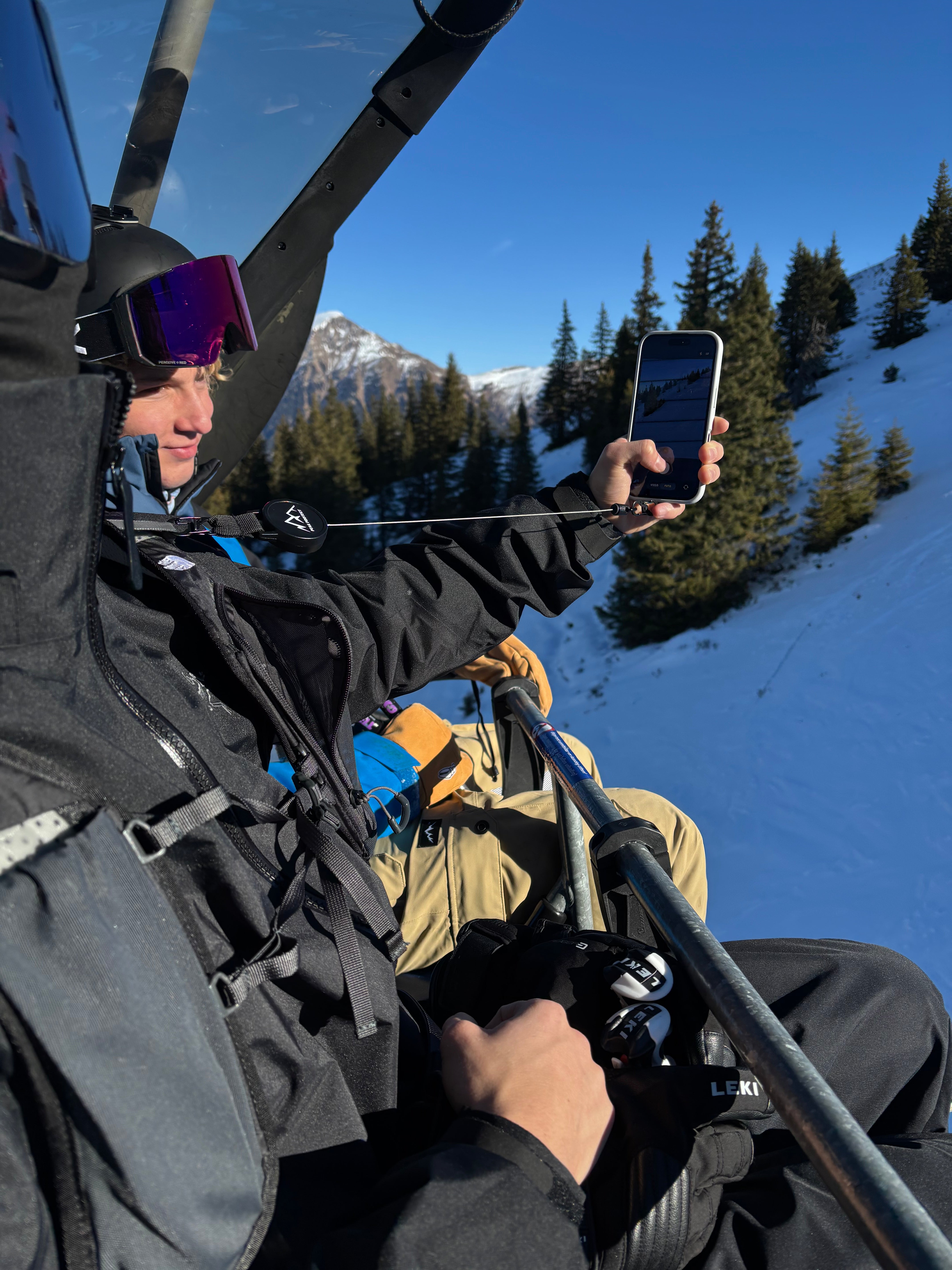 Person nutzt die Easy Protect Smartphone Sicherung auf einem Skilift, um ihr Handy sicher zu verwenden.