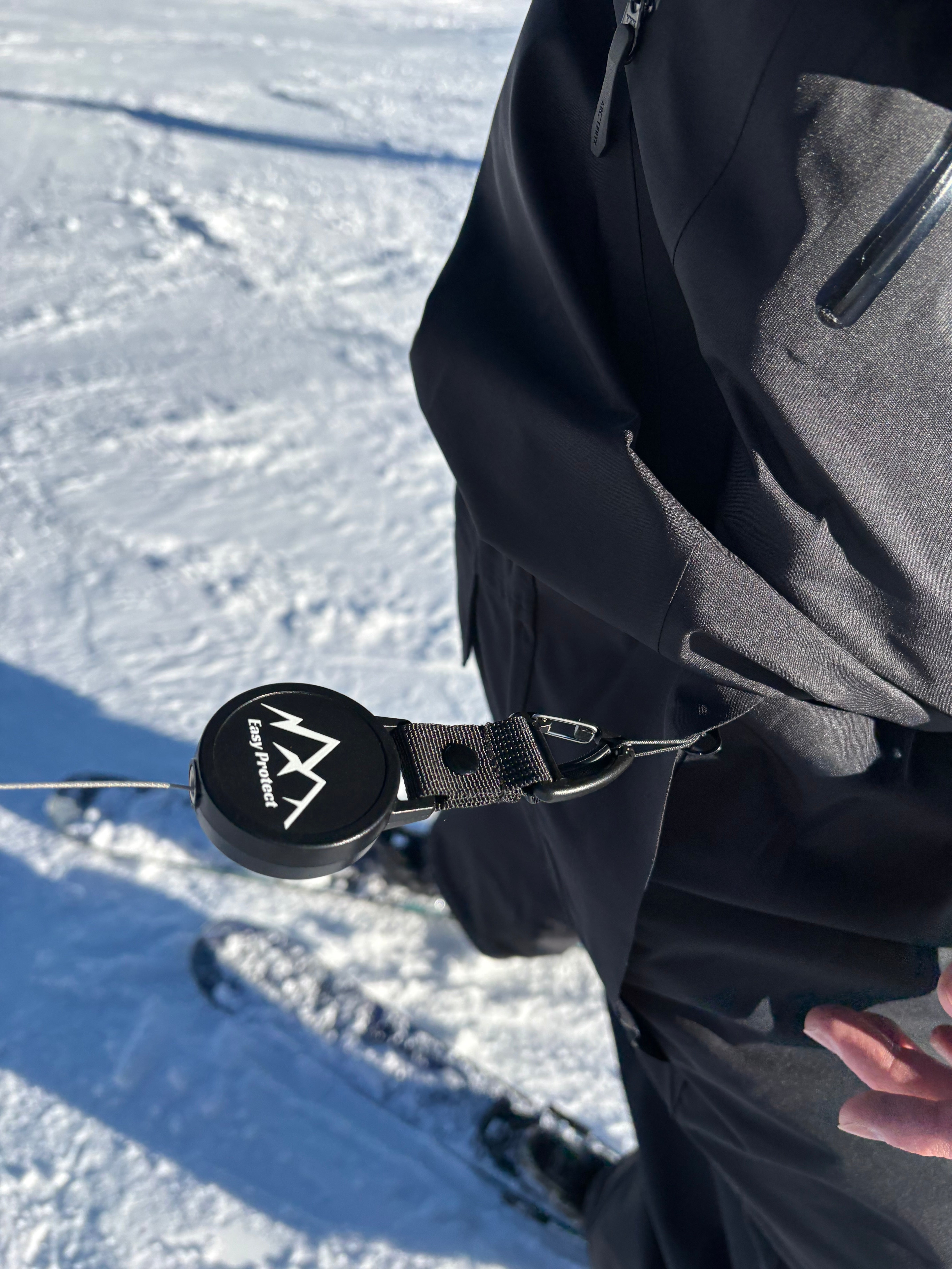 Karabiner der Easy Protect Smartphone Sicherung wird an Kleidung oder Rucksack befestigt.