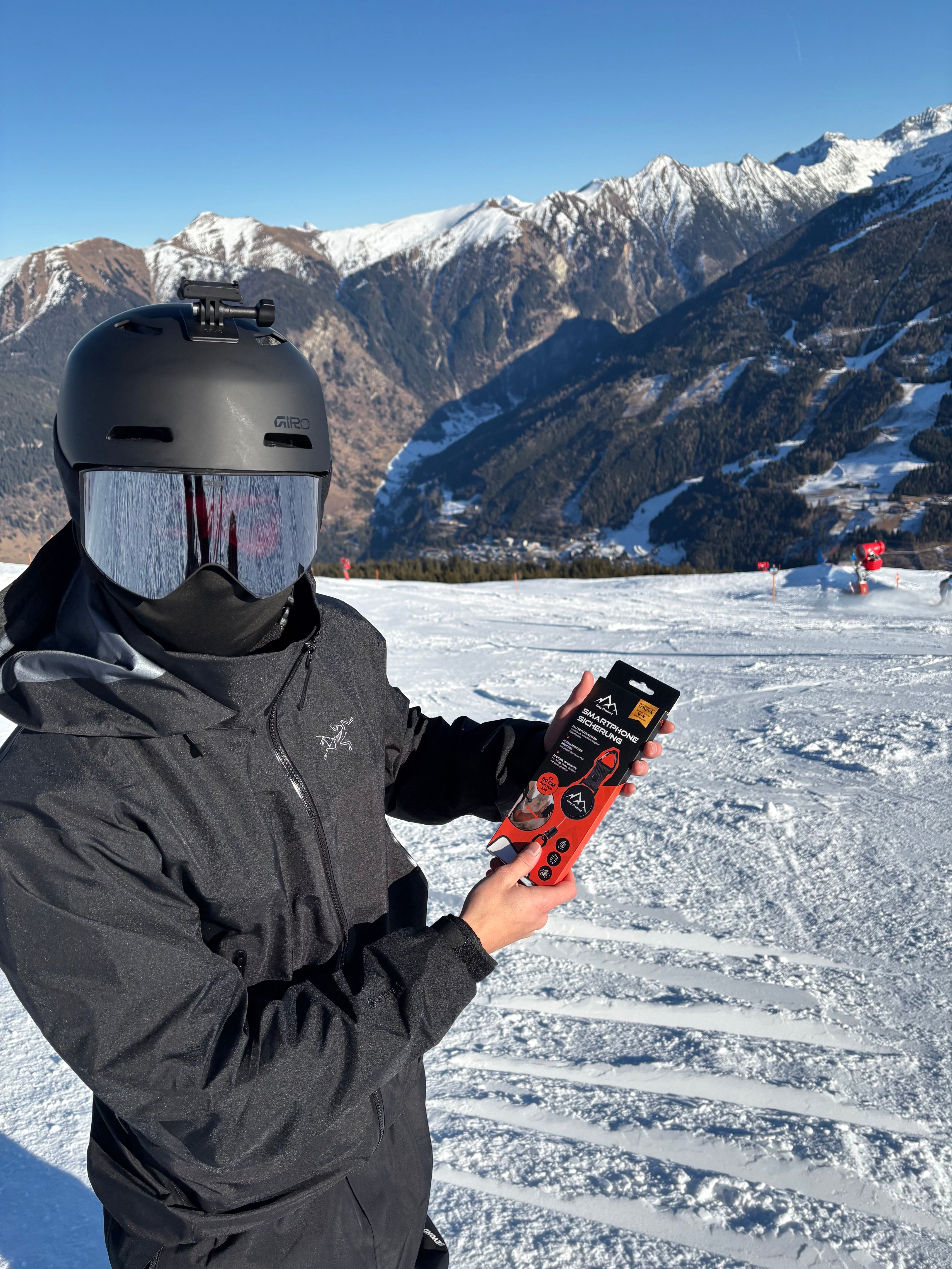 Easy Protect Smartphone Sicherung wird auf einer Skipiste vor einer Berglandschaft präsentiert.