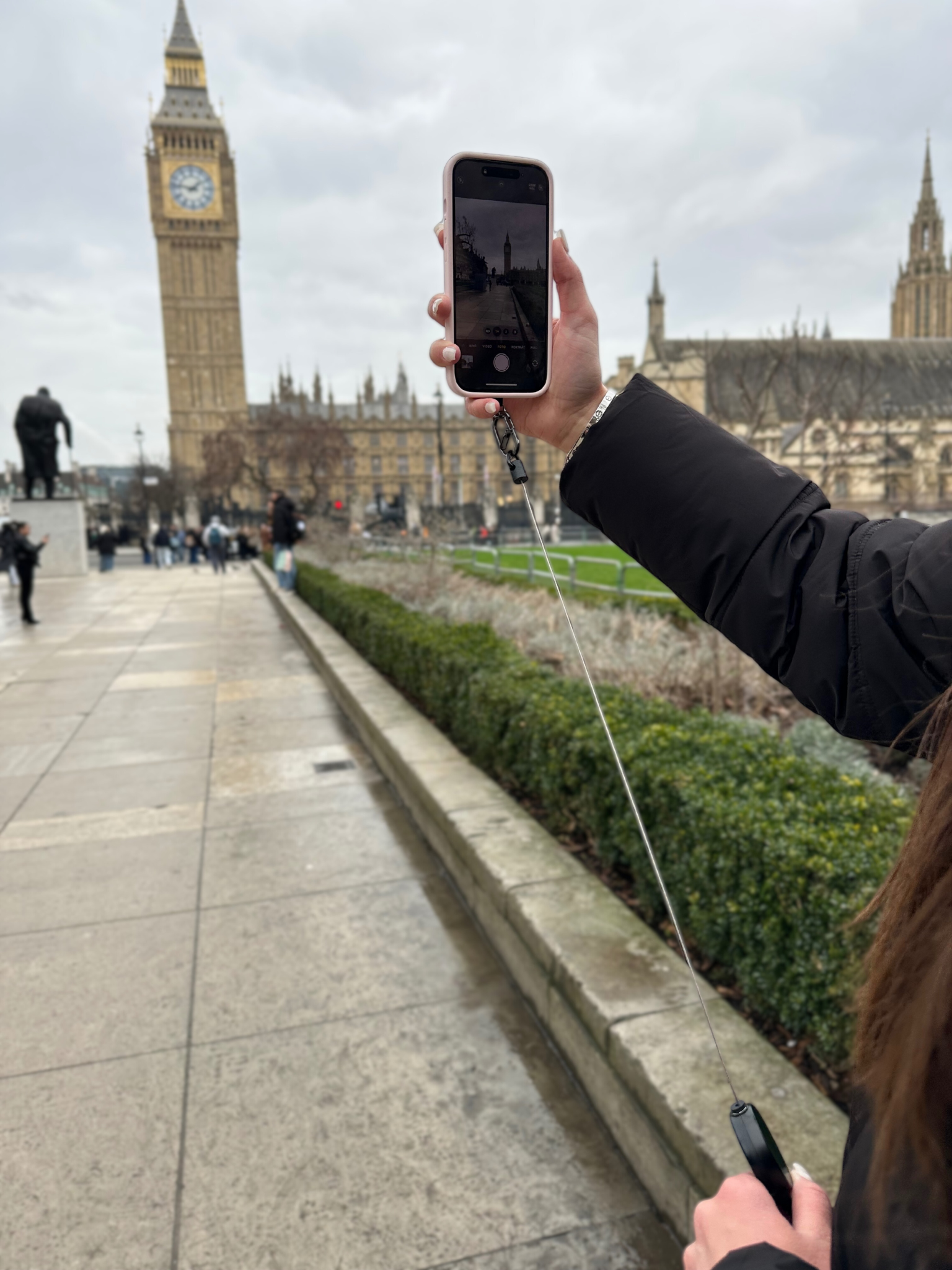 Person nutzt die Easy Protect Smartphone Sicherung beim Fotografieren während eines Städtetrips.