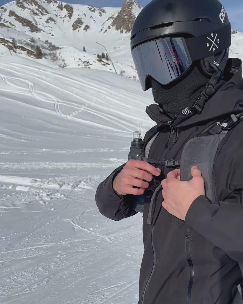 Skifahrer nutzt die Easy Protect Smartphone Sicherung mit ausziehbarem Metallseil, um sein Handy sicher beim Skifahren zu verwenden.